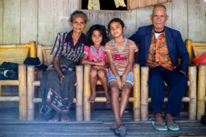 Viona sits outside of her home where she lives with both of her grandparents and younger sister.