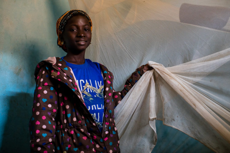 12-year-old Gniré holds onto her mosquito net which hangs above her bed inside of her bedroom on Thursday, January 25, 2018 in Sikasso, Mali. In 2017, Gniré was diagnosed with malaria, twice and then treated. Thanks to Save the children, Gniré has been provided with medication twice a year along with a mosquito net which she sleeps under every night. “I am thankful for Save the Children in my community because it means that they care about my health.”